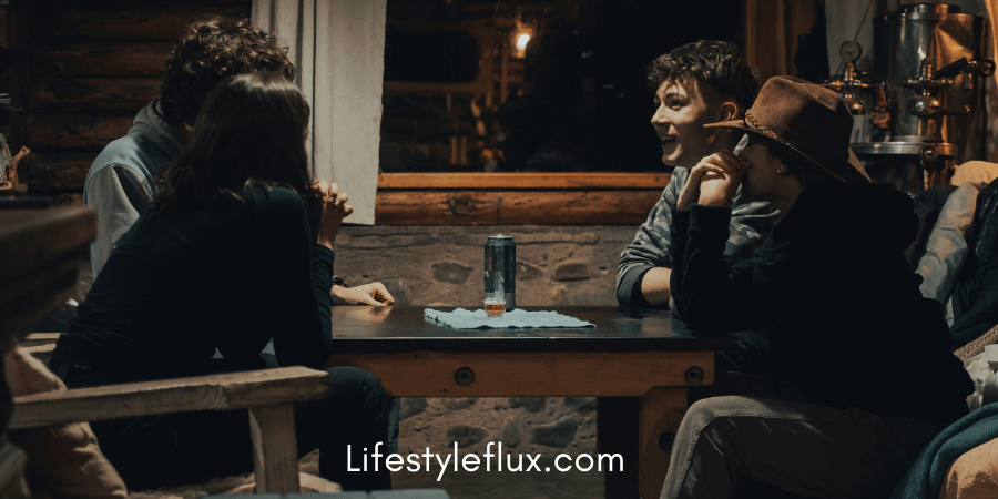 Four young adults are gathered around a table indoors, engaged in conversation.