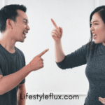 A man and a woman are facing each other, both with open mouths and pointing fingers, suggesting a heated argument.