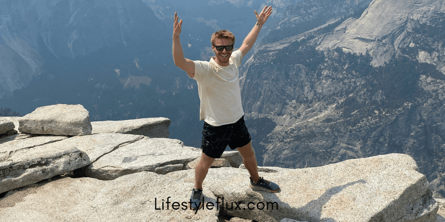 A man standing on a rock with his arms up.